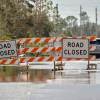 Authorities close a road to keep motorists from driving in flood conditions.