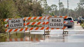Authorities close a road to keep motorists from driving in flood conditions.