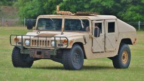 A tan Humvee, or HMMWV, on a grassy field.