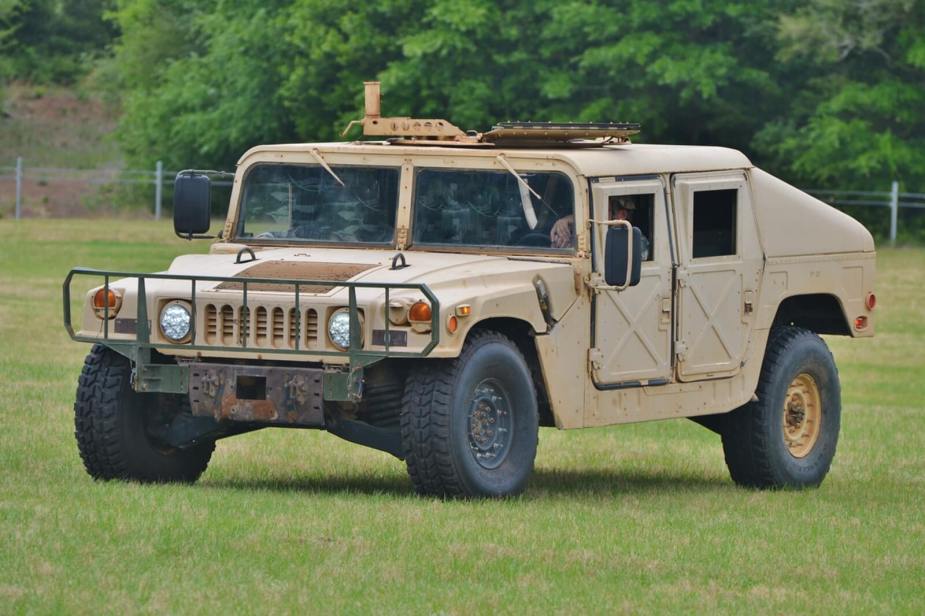 A tan Humvee, or HMMWV, on a grassy field.
