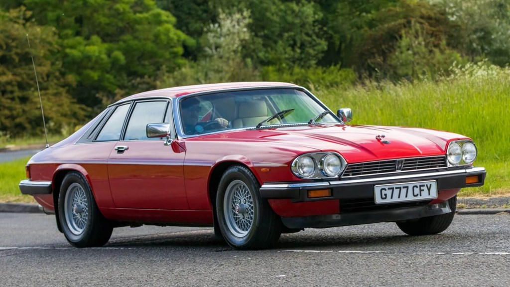 A red Jaguar XJS, a dream car for many, cruises on English roads. 