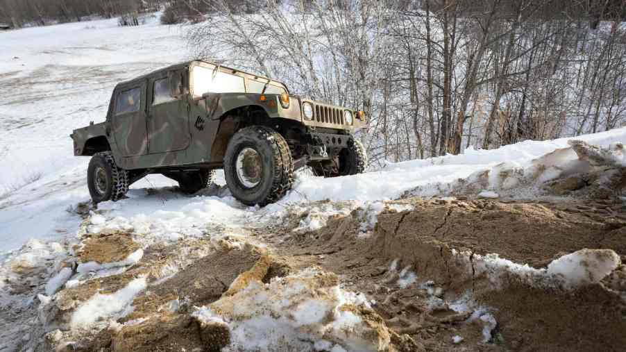 Military surplus Humvee SUV navigating an off-road trail.
