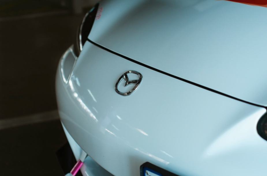The Mazda logo on the hood of a white Miata