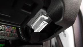 White OBD port under the dashboard of a car.