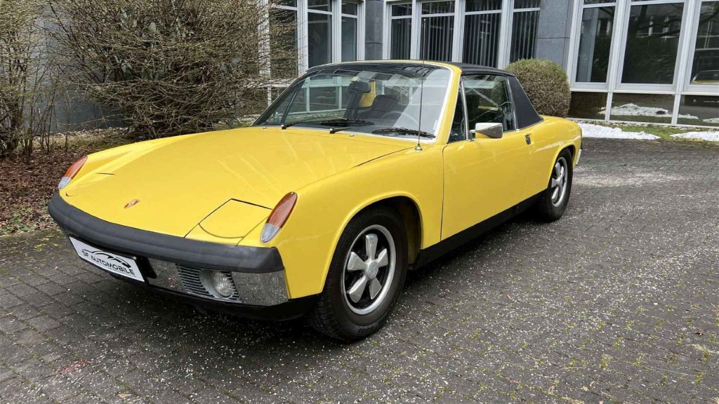 A Yellow Porsche 914 posed on a driveway.