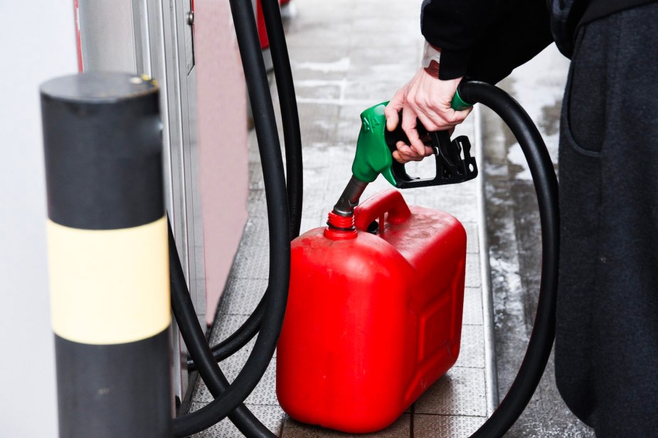 Man fills a gas can at a fuel pump after his car runs out of gas.