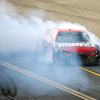 Red NASCAR car doing burnouts on the track