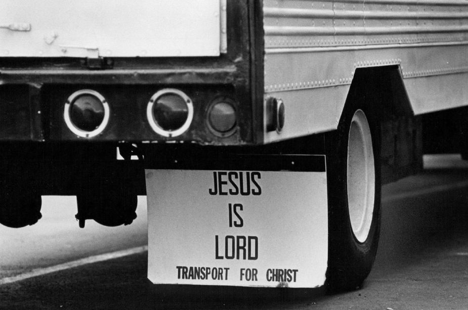 White semi truck trailer with white "Jesus is Lord" mudflaps hanging behind its tires