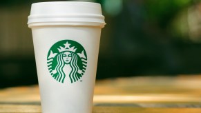 A white Starbucks to-go cup sitting on a wood counter.