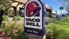 The "Taco Bell Drive Through" sign outside a restaurant, plants visible in the background.