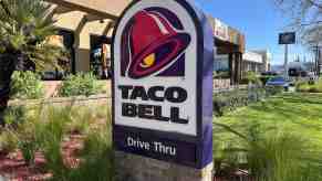 The "Taco Bell Drive Through" sign outside a restaurant, plants visible in the background.