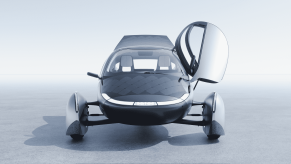 A rendering of the Aptera Launch Edition solar-powered car single passenger trike EV facing directly at viewer with left door wing open