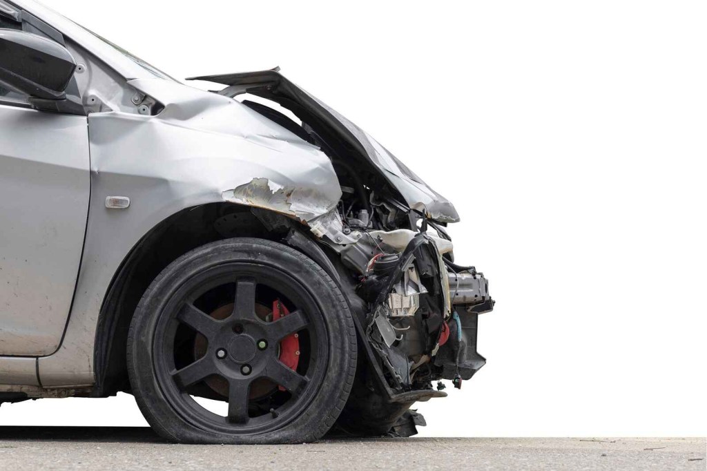 A silver car's nose is shown after a car accident heavy damage close right profile view