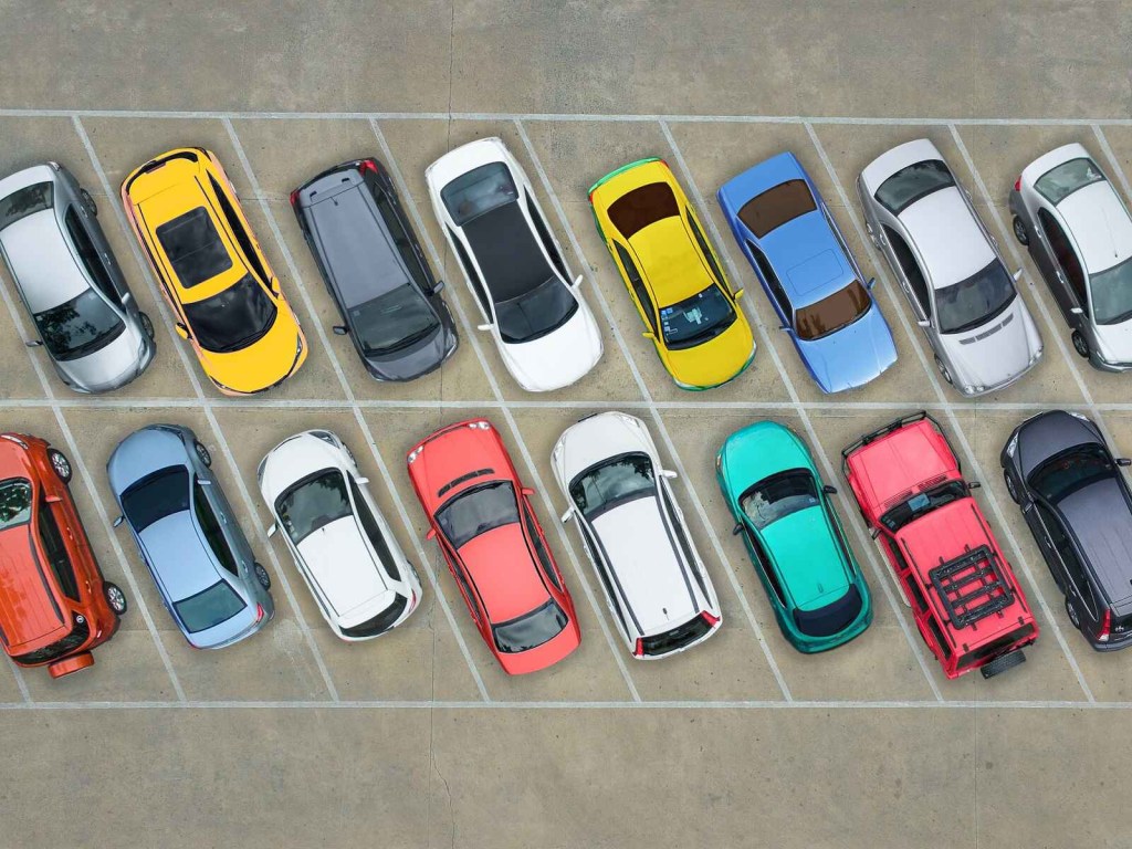 An aerial view of colorful cars lined up in parking spots