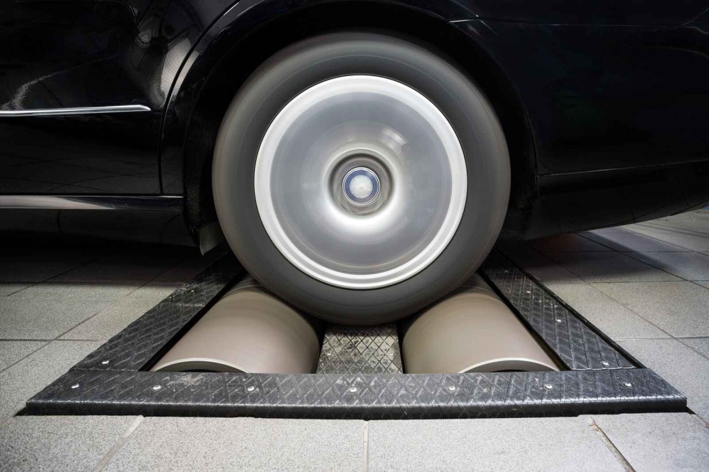 A dyno machine with a car being tested in close view of left rear wheel