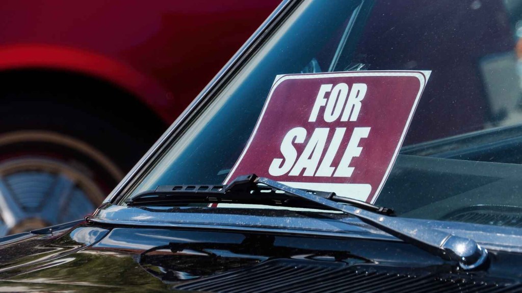 A "for sale" sign on display on a class car's windshield shown in close front view