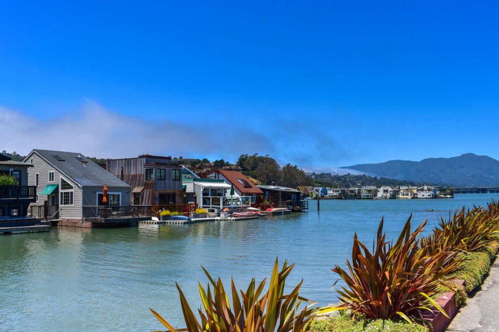 A row of two-story houseboats in the San Francisco Bay Area shown across a waterway