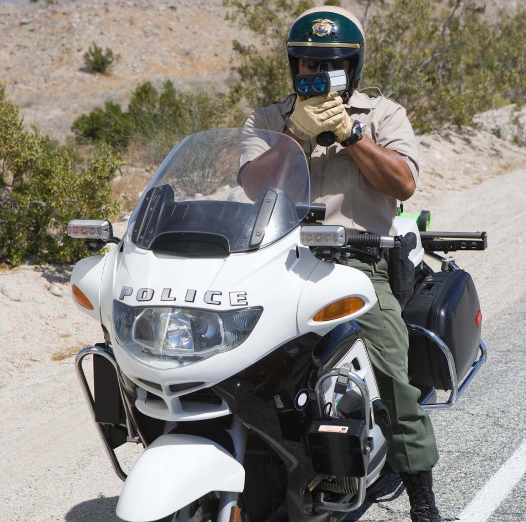 A California Highway Patrol Officer shoots a radar gun. 
