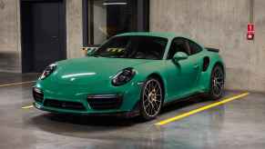 A green Porsche Turbo S parked in a parking garage in left front angle view
