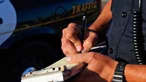 Police officer shown in close view writing a ticket possibly for a primary traffic violation