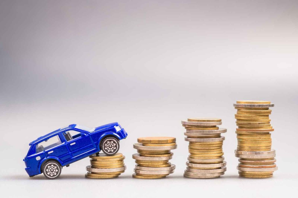 A blue toy car is tipped on onto a short stack of coins in a growing row of stacked coins