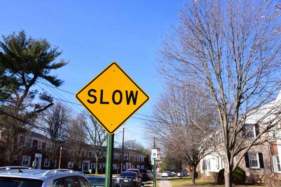 An orange diamond "SLOW" sign on a residential street