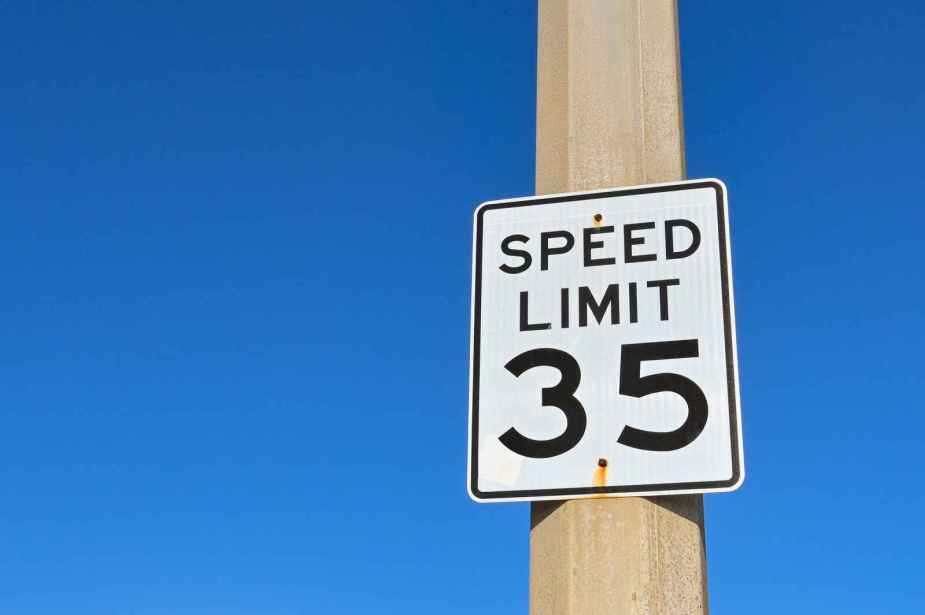 A "speed limit 35" sign posted on a brown pole with a blue background