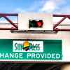 A green sign posted under a stop/go traffic light with the SunPass logo and words "change provided"