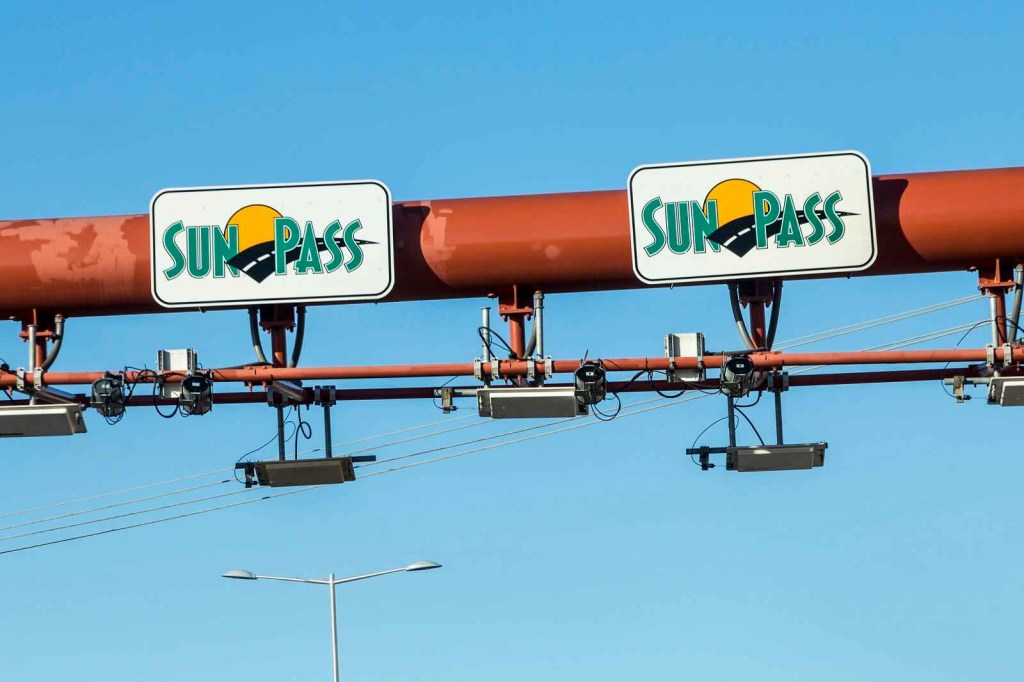 Two SunPass signs posted on a horizonal pole in close view
