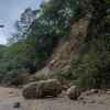 A mountain road in Hualien County, Taiwan blocked by rockfall and fallen debris large boulder in center of road street lamp in left frame