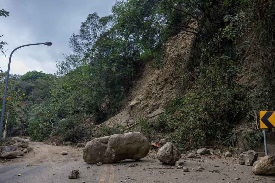 A mountain road in Hualien County, Taiwan blocked by rockfall and fallen debris large boulder in center of road street lamp in left frame