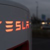 Tesla supercharger in very close top view at night with "Tesla" logo backlit in orange lighting