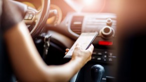 Woman's arm holding a cell phone while driving