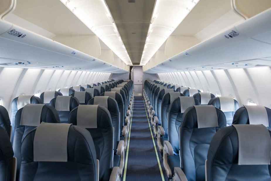 The empty cabin of a commercial plane blue seats with cabin lights turned on