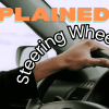 An image of a hand on a car steering wheel with the words "Explained! Steering Wheel Shakes"