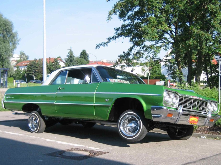 Bright green Chevrolet Impala lowrider on hydraulics with one wheel off the ground.