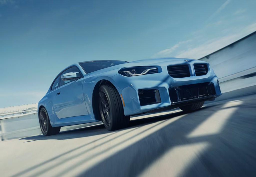A blue 2024 BMW M2 gets sideways on a track.