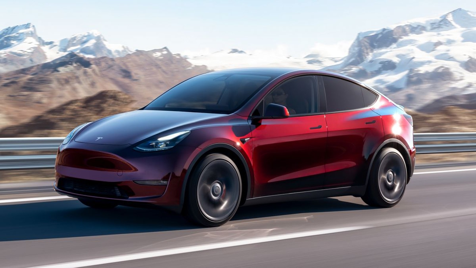 Red 2024 Tesla Model Y electric SUV driving on a road.