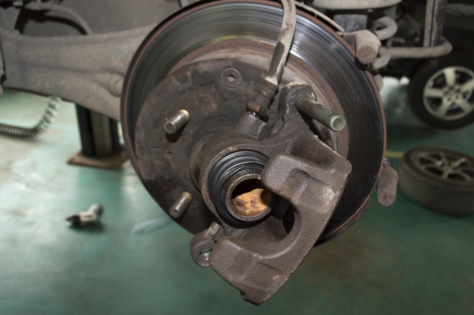 A brake caliper with exposed piston removed from the brake rotor during maintenance.