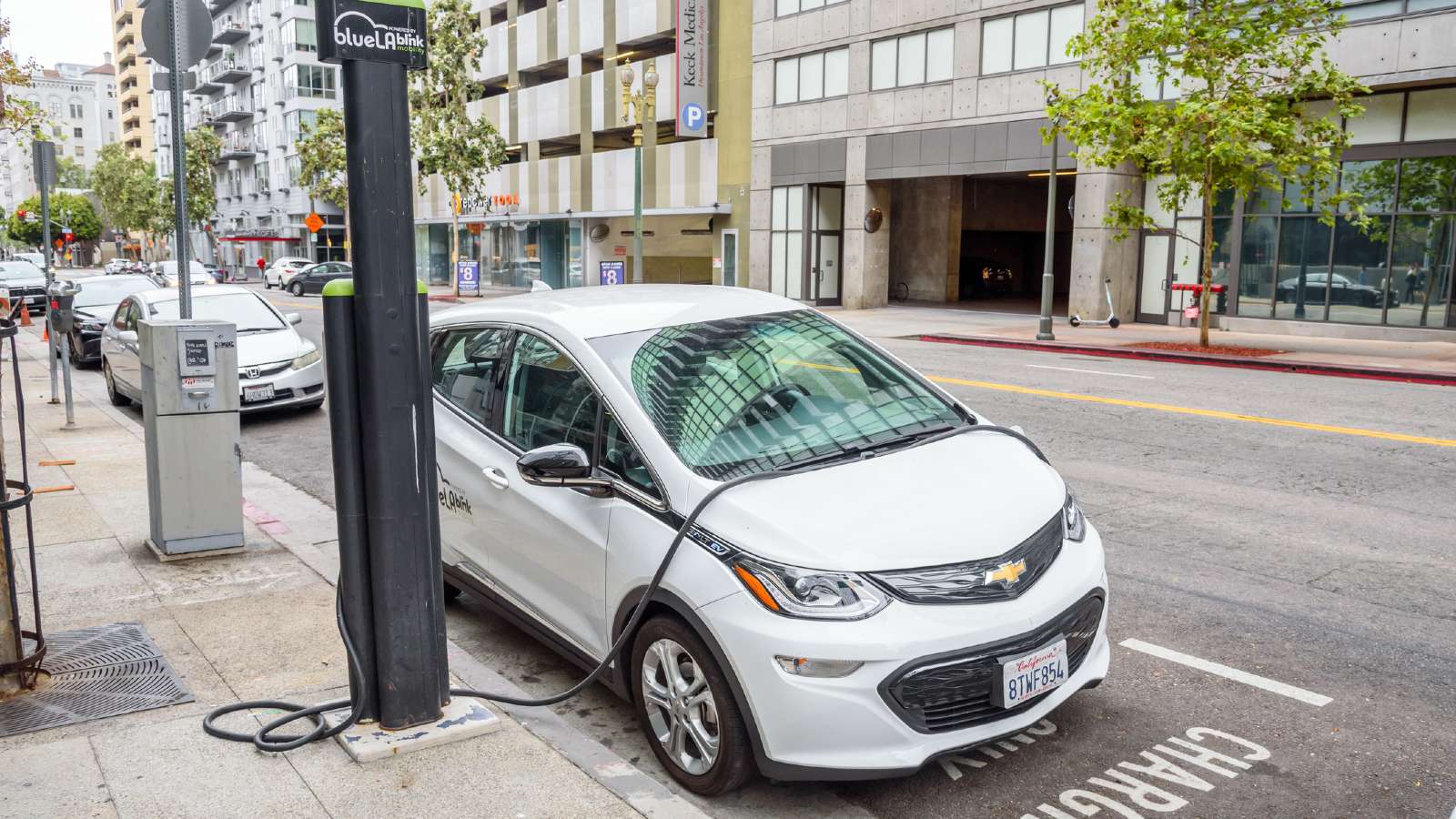 Electic Car Charging at a Public Charger located on a sidewalk, This charger gets in the way of people walking on the sidewalk.