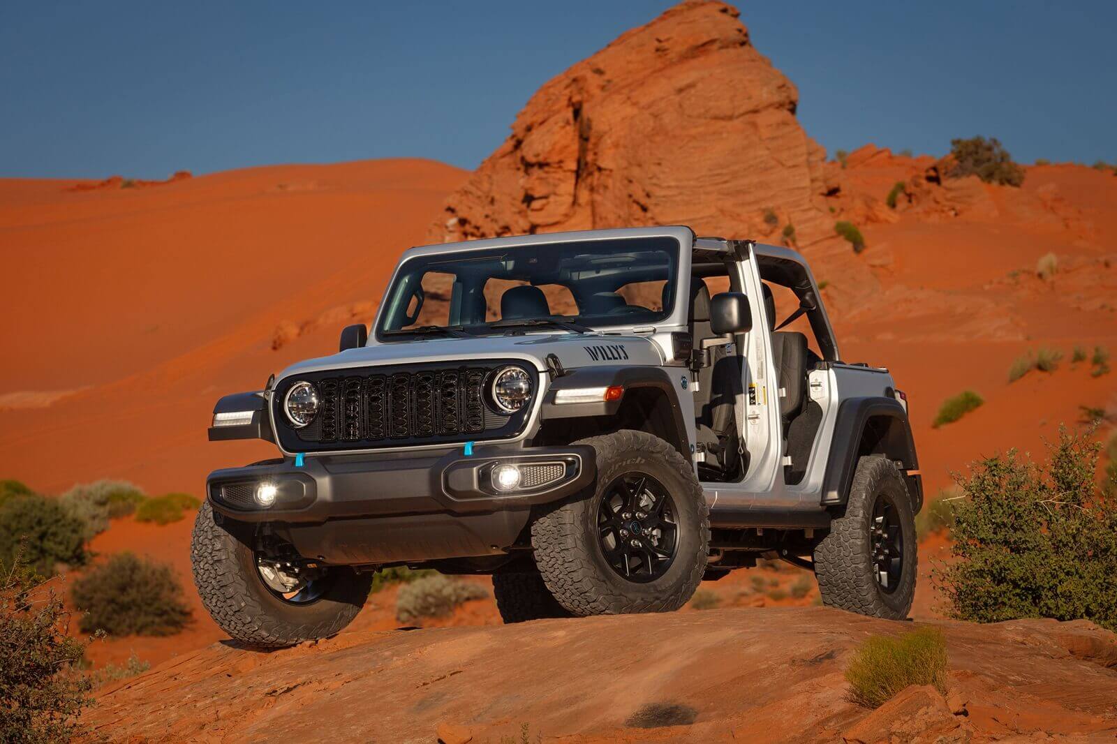 A silver Jeep Wrangler 4xe Willys PHEV shows off its modularity in the desert. 