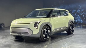 Yellow Kia EV3 subcompact electric crossover posed on stage.