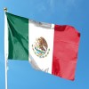 Mexican flag on a pole, a blue sky visible in the background.