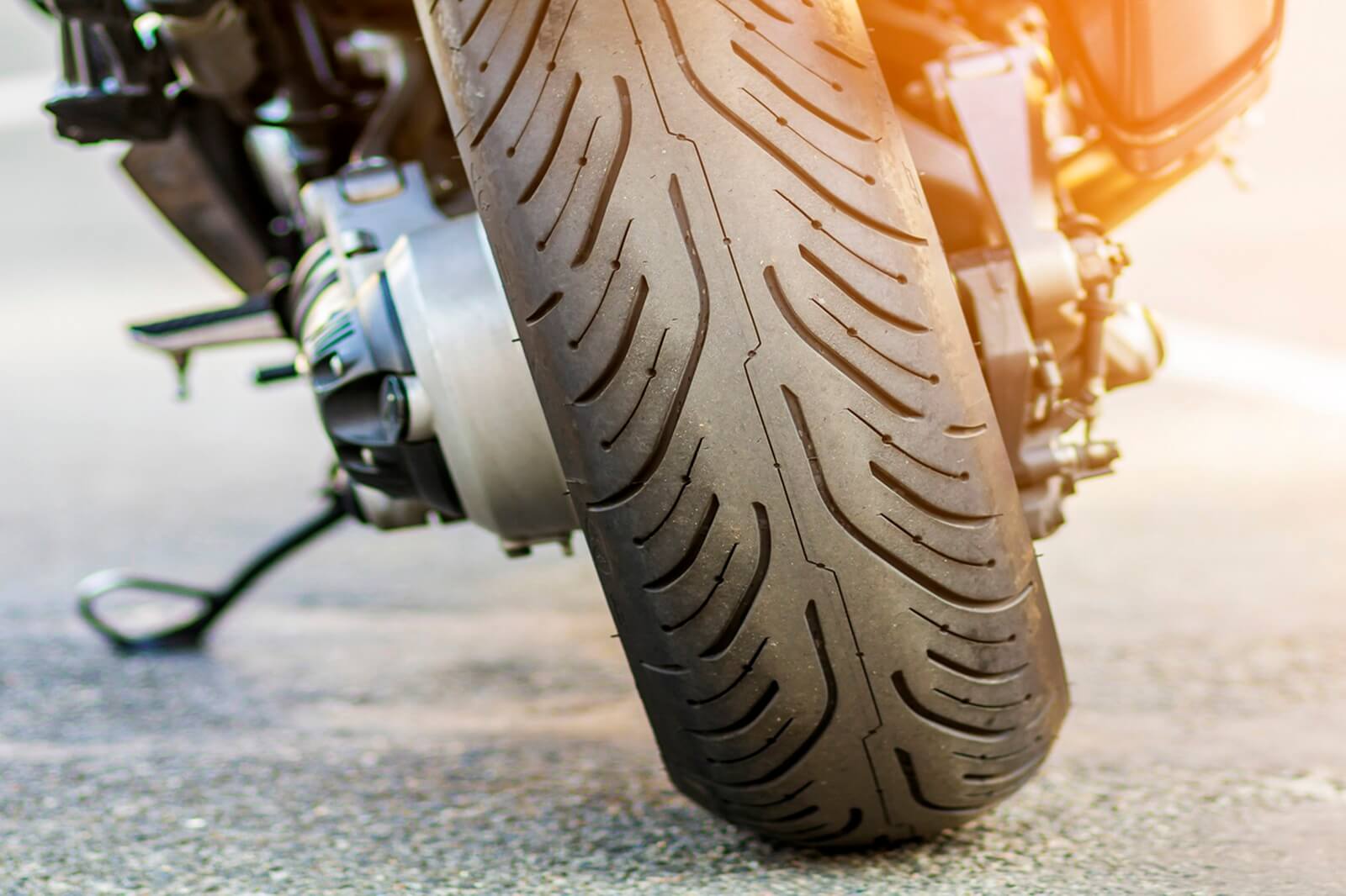 The rear tire of a motorcycle on a kickstand.