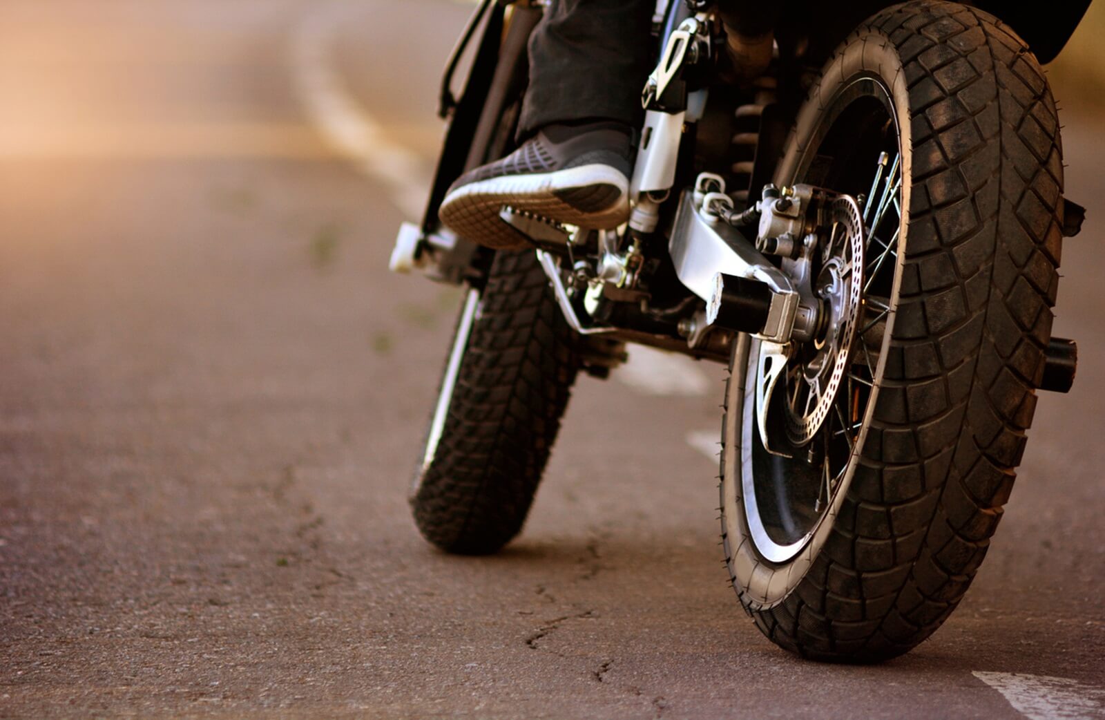 A motorcycle leans on its front and rear tire.