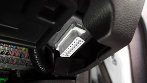 White plastic OBD port under a car's dashboard.