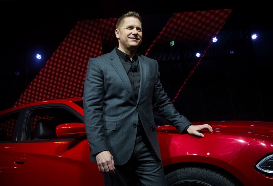 Dodge CEO Tim Kuniskis leans on a Charger sedan.