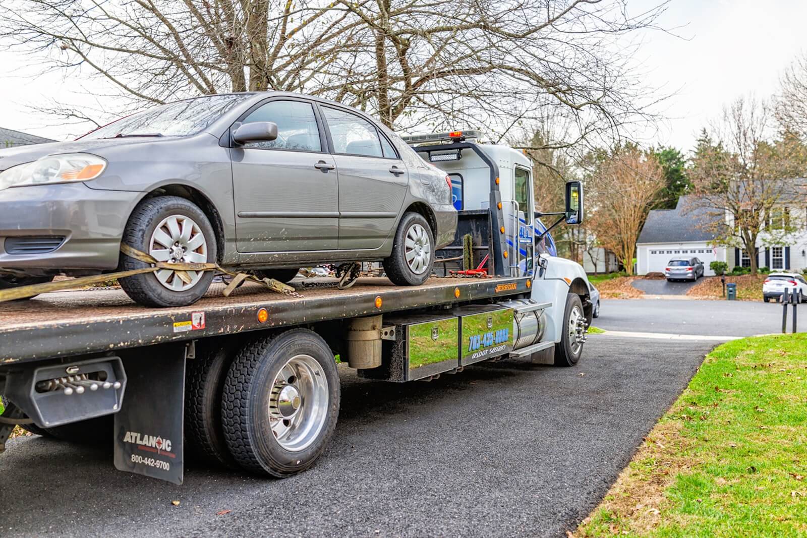 A flatbed truck picks up a Toyota sedan after a roadside assistance call. 