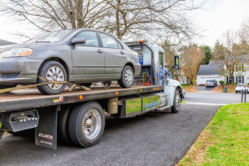 A flatbed truck picks up a Toyota sedan after a roadside assistance call.