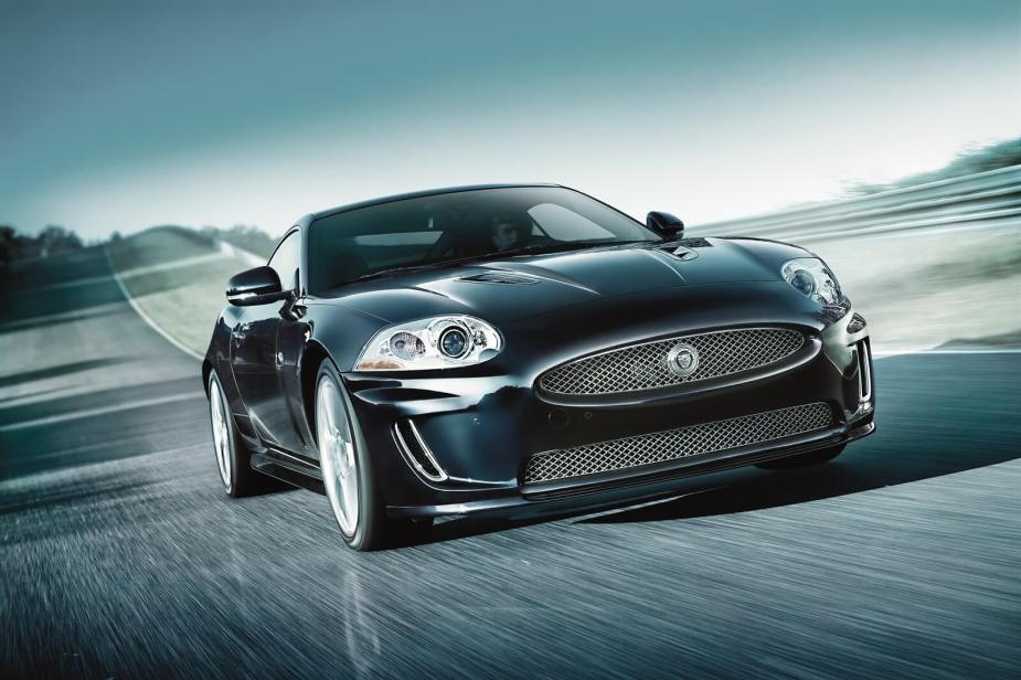 An X150 Jaguar XKR dashes around a corner on an empty road.
